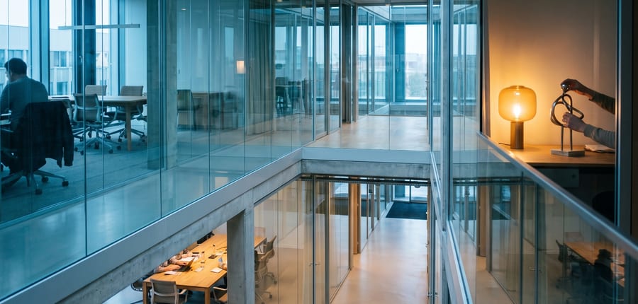 A glass-walled office interior seen from a mezzanine